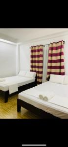 two beds in a room with striped curtains at Villa Malinao Oceanview Resort - Deluxe bungalow in Burgos