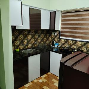 une cuisine avec des placards blancs et un comptoir noir dans l'établissement The Dream House, à Kottayam