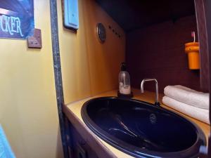 uma casa de banho com um lavatório preto e uma garrafa de sabão em The Captains Locker - 30ft Yacht em San Miguel de Abona