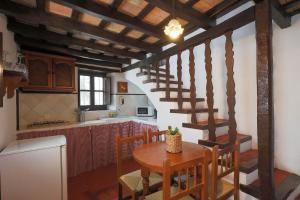 cocina y comedor con mesa y escaleras en Casas Rurales Tugasa Castillo de Castellar, en Castellar de la Frontera