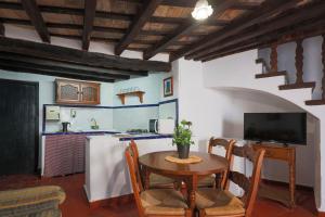 a kitchen and dining room with a table and a tv at Casas Rurales Tugasa Castillo de Castellar in Castellar de la Frontera