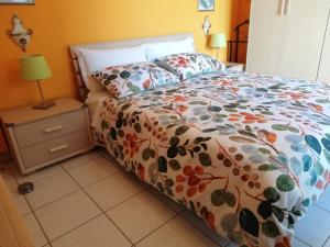 a bed with a colorful comforter and a night stand at Attico luminoso I colori del sole in Montesilvano