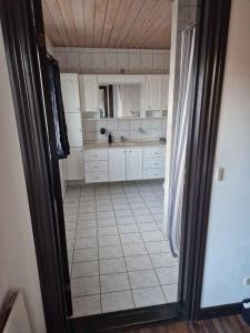 a kitchen with white cabinets and a tiled floor at Townhouse With Nature As Neighbor in Brande