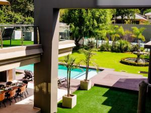 vista esterna su un giardino con palme e piscina di One O Eight Boutique Hotel a Benoni