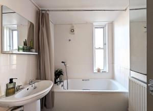 een witte badkamer met een bad en een wastafel bij Riverside apartment in Islington in Londen