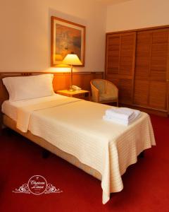 Habitación de hotel con cama y silla en Chateau Linza Resort en Tirana