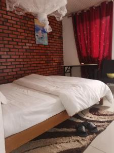 a bed in a room with a red brick wall at Alink chinese and korean restaurent in Kigali