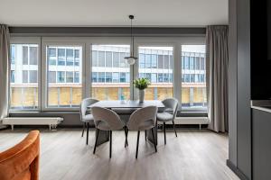 a dining room with a table and chairs and windows at numa l Saga Apartments in Bremen