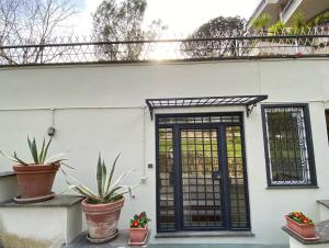una casa bianca con una porta nera e piante in vaso di Camilluccia Dream Apartment a Roma