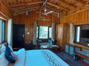 1 dormitorio con cama, sofá y TV en Alinda House Naukuchiatal by THE GHAUR en Bhīm Tāl