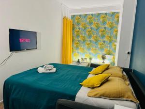 - une chambre avec un lit bleu avec des oreillers jaunes et une télévision dans l'établissement Ipanema, au Centre ville de Lens, à Lens