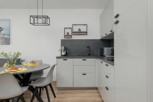 科沃布熱格的住宿－Exclusive and Modern Grey Apartment with Furnished Balcony in Kołobrzeg by Renters，厨房配有白色橱柜和桌椅