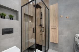 La salle de bains est pourvue d'une douche avec une porte en verre. dans l'établissement Exclusive and Modern Grey Apartment with Furnished Balcony in Kołobrzeg by Renters, à Kołobrzeg