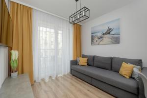 a living room with a gray couch and a window at Exclusive and Modern Grey Apartment with Furnished Balcony in Kołobrzeg by Noclegi Renters in Kołobrzeg