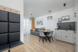 a kitchen and a living room with a table at Exclusive and Modern Grey Apartment with Furnished Balcony in Kołobrzeg by Noclegi Renters in Kołobrzeg +12 photos