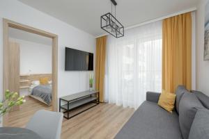 a living room with a couch and a mirror at Exclusive and Modern Grey Apartment with Furnished Balcony in Kołobrzeg by Noclegi Renters in Kołobrzeg