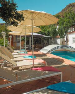 un grupo de sillas y una sombrilla junto a una piscina en El Estanco 14 en Vega de San Mateo