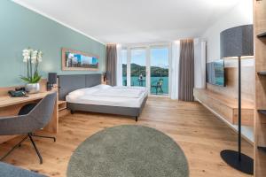 a bedroom with a bed and a view of the water at AllgäuStern Hotel in Sonthofen