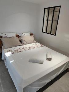 a large white bed in a room with a window at Jacuzzi, Sauna, Piscine et Magnifique Vue sur la Mer ! Vivez le Luxe de la Dépendance de la Villa Nadia in Le Diamant