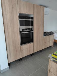 a kitchen with a wooden cabinet with a oven at Jacuzzi, Sauna, Piscine et Magnifique Vue sur la Mer ! Vivez le Luxe de la Dépendance de la Villa Nadia in Le Diamant
