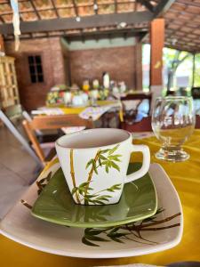 a coffee cup sitting on a plate on a table at Pousada Nativo's in Nova Almeida