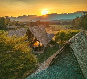 eine Luftansicht eines Hauses mit Sonnenuntergang im Hintergrund in der Unterkunft Cody Backpackers in Pai