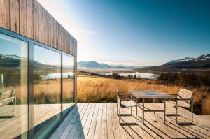 eine Holzterrasse mit einem Tisch und Stühlen auf einem Gebäude in der Unterkunft Villa Lola in Akureyri