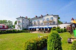 een groot wit huis met een tuin met een vijver bij Hotel Residence in Rewal