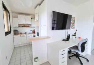 a white kitchen with a desk and a tv on the wall at L'Artiste in Soisy-sous-Montmorency