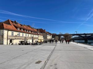 a group of people walking down a street next to a bridge at Old Town's Legend: City center condo with balcony in Maribor