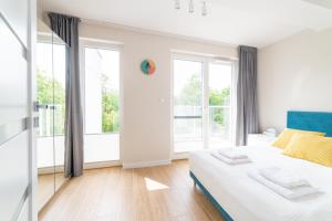 a white bedroom with a bed and large windows at Apartamenty In Mestwina 37 Jurata in Jurata