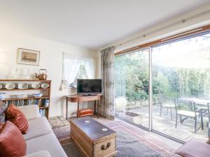 a living room with a tv and a large window at Ivy Cottage in West Mersea