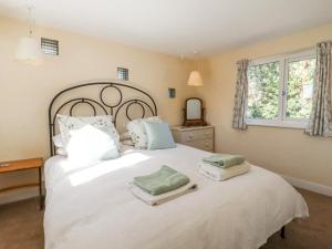 a bedroom with a large white bed with towels on it at Ivy Cottage in West Mersea