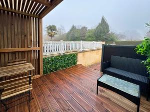a wooden deck with a bench and a white fence at Tiny House moderne à Disneyland in Coutevroult