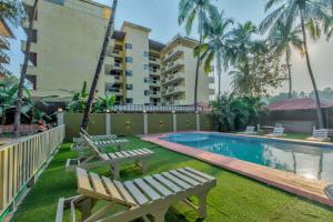a resort with a swimming pool and two benches at Rosa Bella Resort-TBV in Calangute