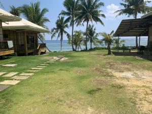 a yard next to a house with palm trees and the ocean at Villa Malinao Oceanview Resort - Deluxe bungalow in Burgos +8 photos