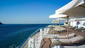 una terraza con tumbonas y sombrillas en el océano en Park Plaza Histria Pula en Pula