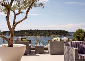 eine Gruppe Stühle und ein Baum auf einer Terrasse in der Unterkunft Park Plaza Histria Pula in Pula