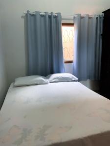 uma cama num quarto com uma janela com cortinas em Casa conforto em Pirenópolis