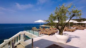 a deck with lounge chairs and a tree on the ocean at Park Plaza Verudela Pula in Pula