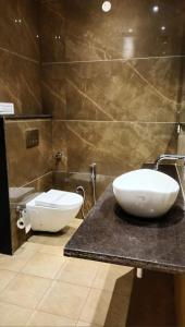 a bathroom with a sink and a toilet on a counter at HOTEL PEARL WOOD (A unit of olive hospitality group) in Zirakpur