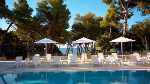 a group of chairs and umbrellas next to a swimming pool at Park Plaza Arena Pula in Pula