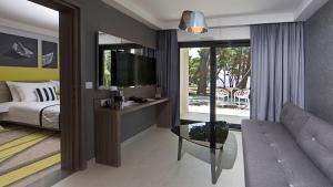 a bedroom with a bed and a tv and a couch at Park Plaza Arena Pula in Pula
