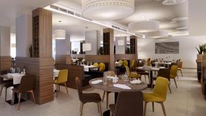 a restaurant with tables and chairs in a room at Park Plaza Arena Pula in Pula