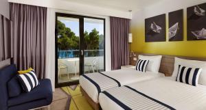 a hotel room with two beds and a balcony at Park Plaza Arena Pula in Pula