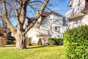 une maison blanche avec un arbre dans la cour dans l'établissement Friedenstraße 7 Whg 4, à Zingst