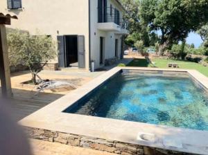 - une piscine en face d'une maison dans l'établissement Belle villa avec piscine et vue mer- Hauteurs de Bastia, à Bastia