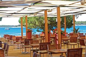 ein Restaurant mit Tischen und Stühlen neben dem Wasser in der Unterkunft Park Plaza Belvedere Medulin in Medulin