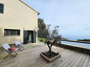 une terrasse en bois avec deux chaises et un arbre dans l'établissement Belle villa avec piscine et vue mer- Hauteurs de Bastia, à Bastia