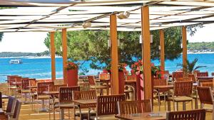 a restaurant with tables and chairs and the ocean at Park Plaza Belvedere Medulin in Medulin